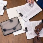 Top view of a business meeting with hands, tablets, and documents on a table.